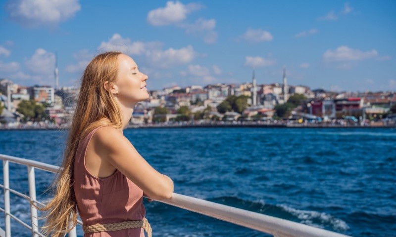 Srećna žena uživa u moru sa trajekta koji prelazi Bosfor u Istanbulu