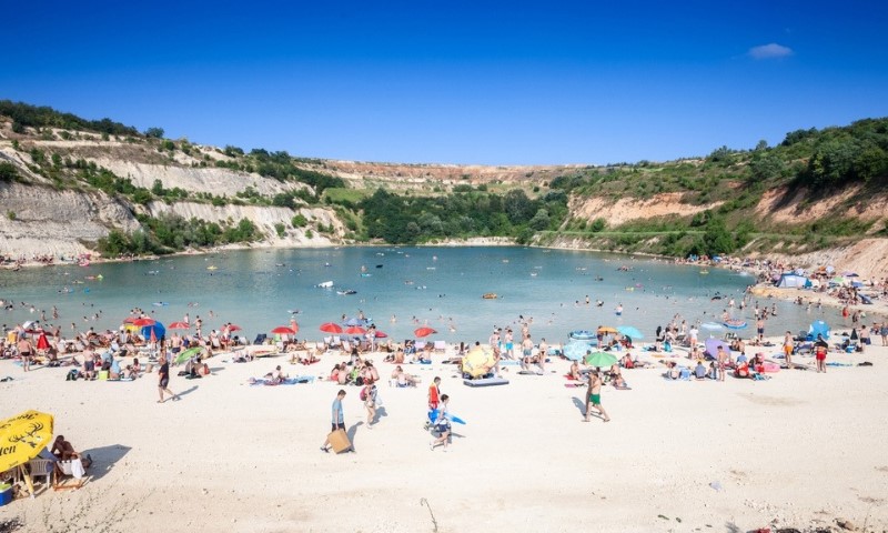 Plaža sa ljudima koji se sunčaju ispred Bešenovačkog jezera